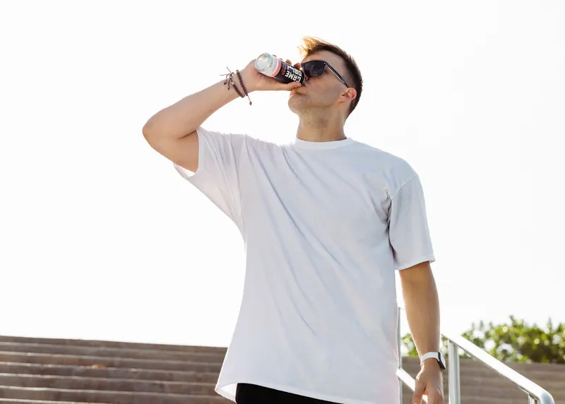 A GameDay Spiked can held over a poolside rail, condensation running down it